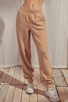 Beige pants standing against a white curtain.