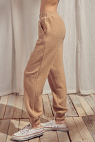 Side view of beige pants standing against a white curtain.