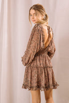 Back view of a woman wearing a brown dress with a floral pattern and an open back with self-tie straps