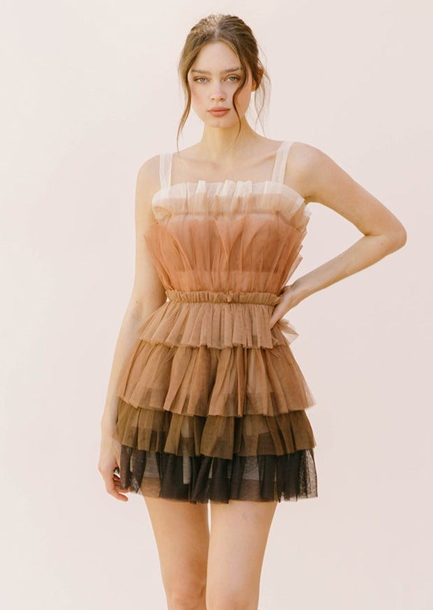 A model wearing a brown mini dress with layered tulle and spaghetti straps.