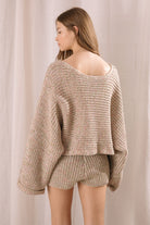 Back view of a woman wearing a knitted outfit against a plain background