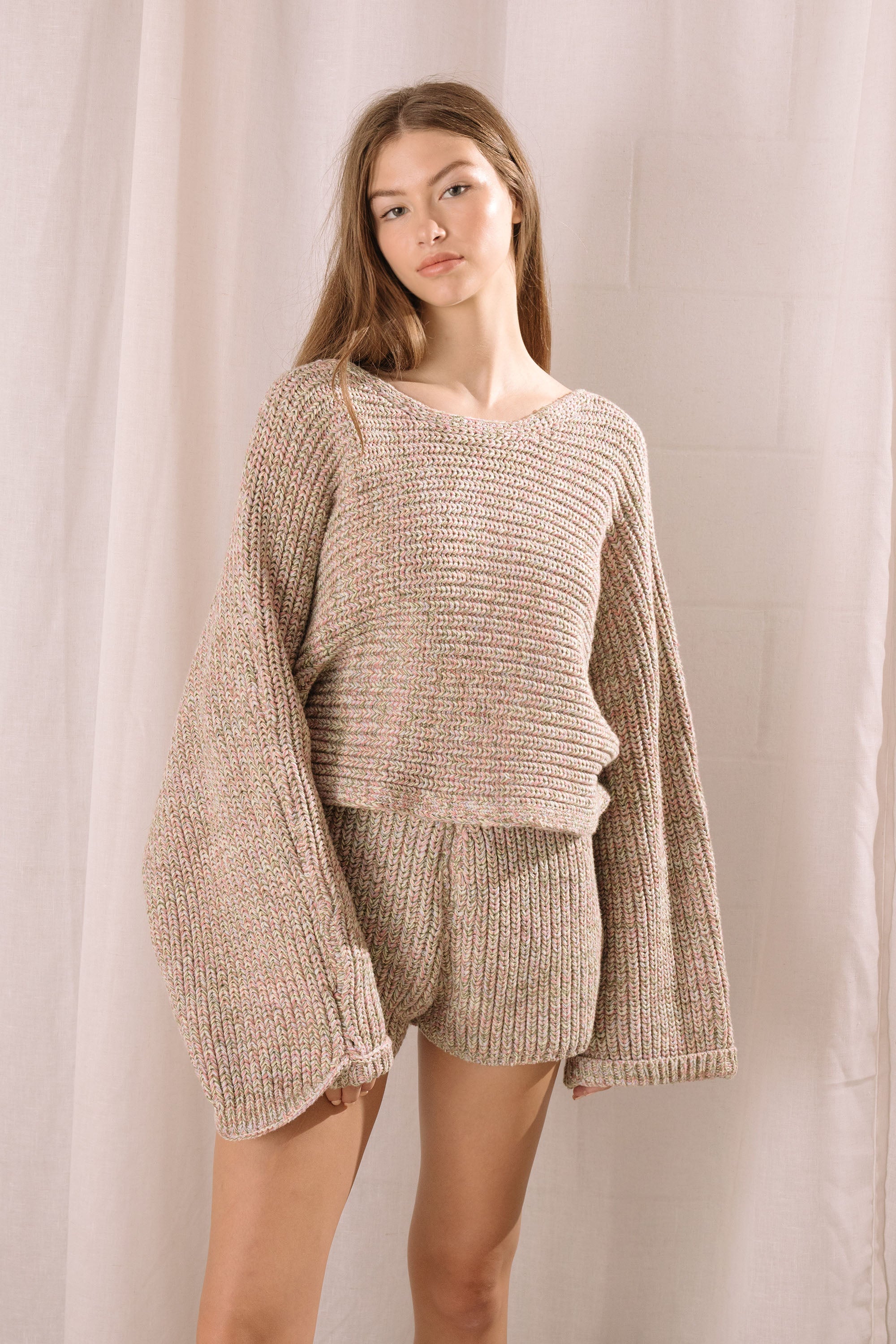 Woman wearing a knitted outfit against a plain background