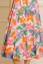 Colorful floral dress standing against a beige curtain.