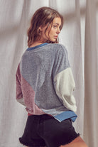 Back view of a woman wearing a color block sweatshirt with round neckline with a plain background