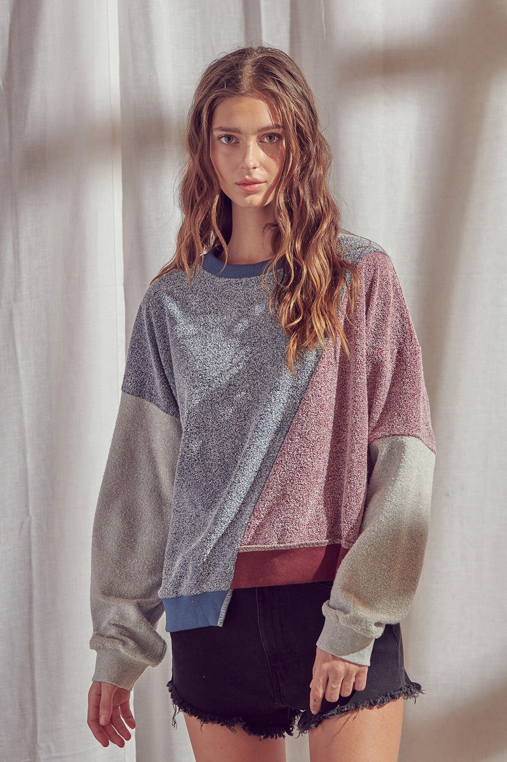 Woman wearing a color block sweatshirt with round neckline with a plain background