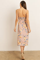 Back view of a woman wearing a mauve floral dress on a plain background