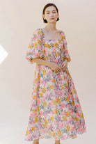 Woman wearing a pink floral midi dress against a plain background