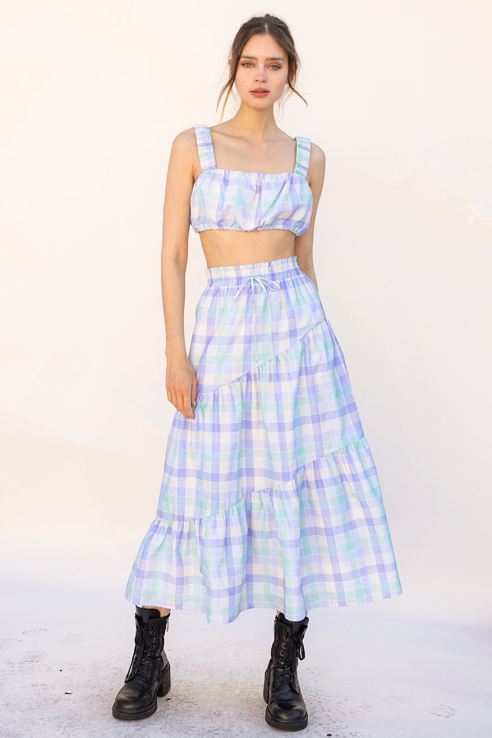 Woman wearing a pastel plaid top and skirt set with a white background