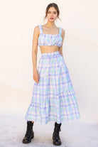 Woman wearing a pastel plaid top and skirt set with a white background
