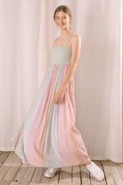 Side view of a woman wearing a pastel striped dress standing against a plain background