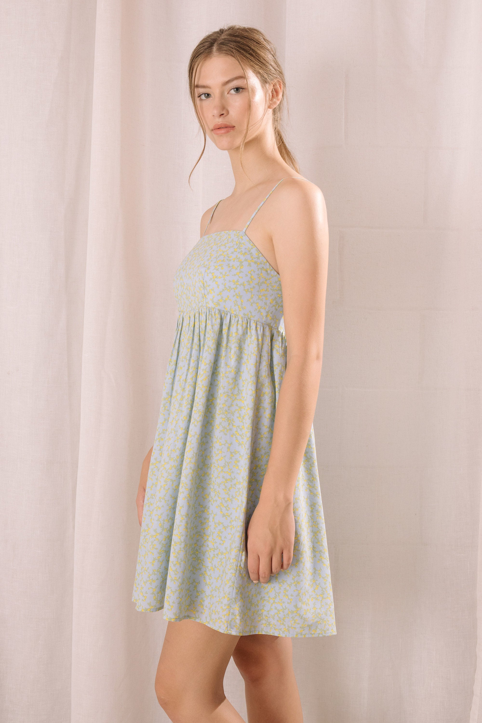 Side view of a woman wearing a light blue dress against a plain background
