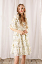 Woman wearing a floral dress against a white curtain background
