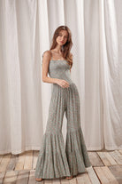 Woman wearing a green jumpsuit with a floral pattern and palazzo wide-leg pants.