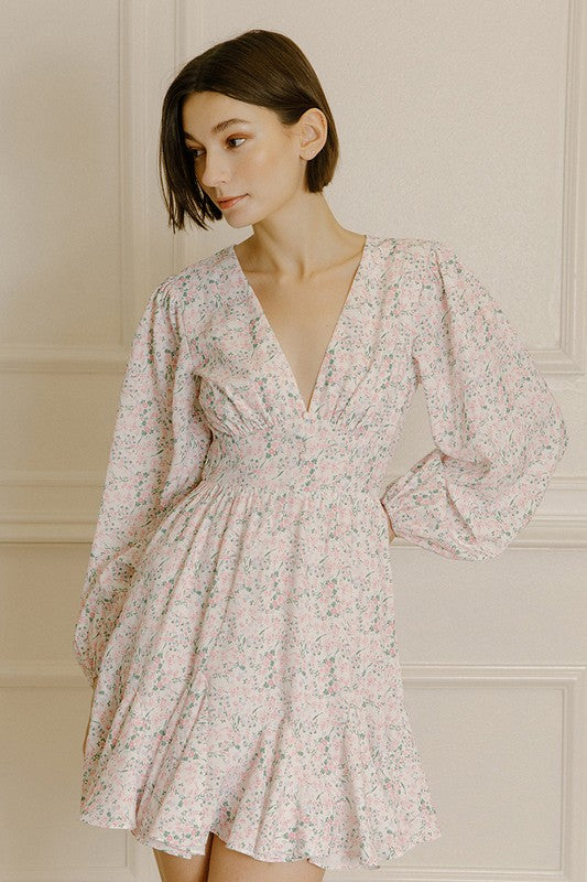 Woman wearing a pink dress with a floral pattern against a neutral background