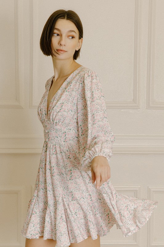 Woman wearing a pink dress with a cinched waist and a floral pattern against a neutral background