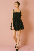 Woman wearing a black tulle dress against a pink background