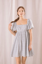 Woman wearing a light blue floral dress against a plain background