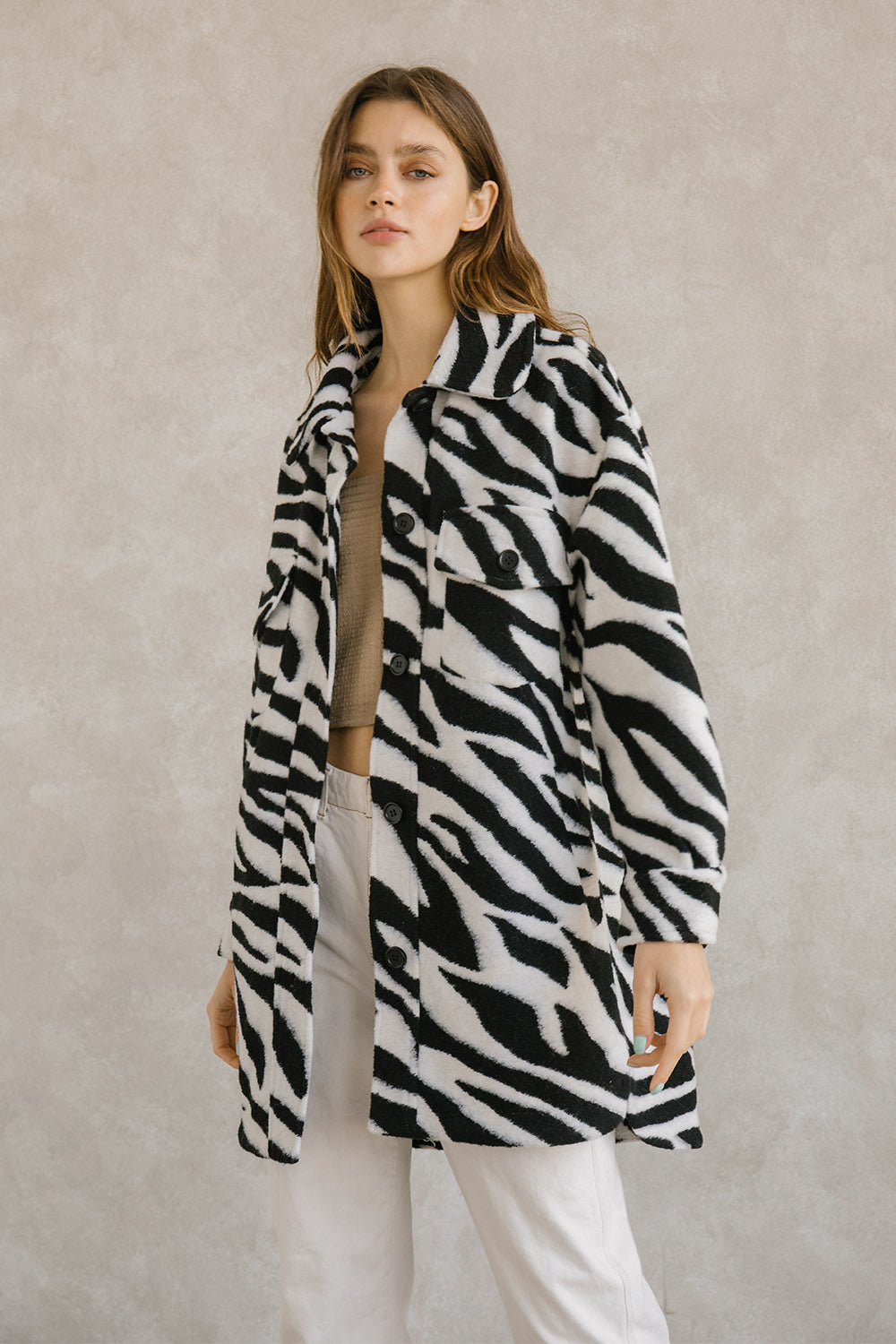 Woman wearing a zebra-patterned coat against a plain background