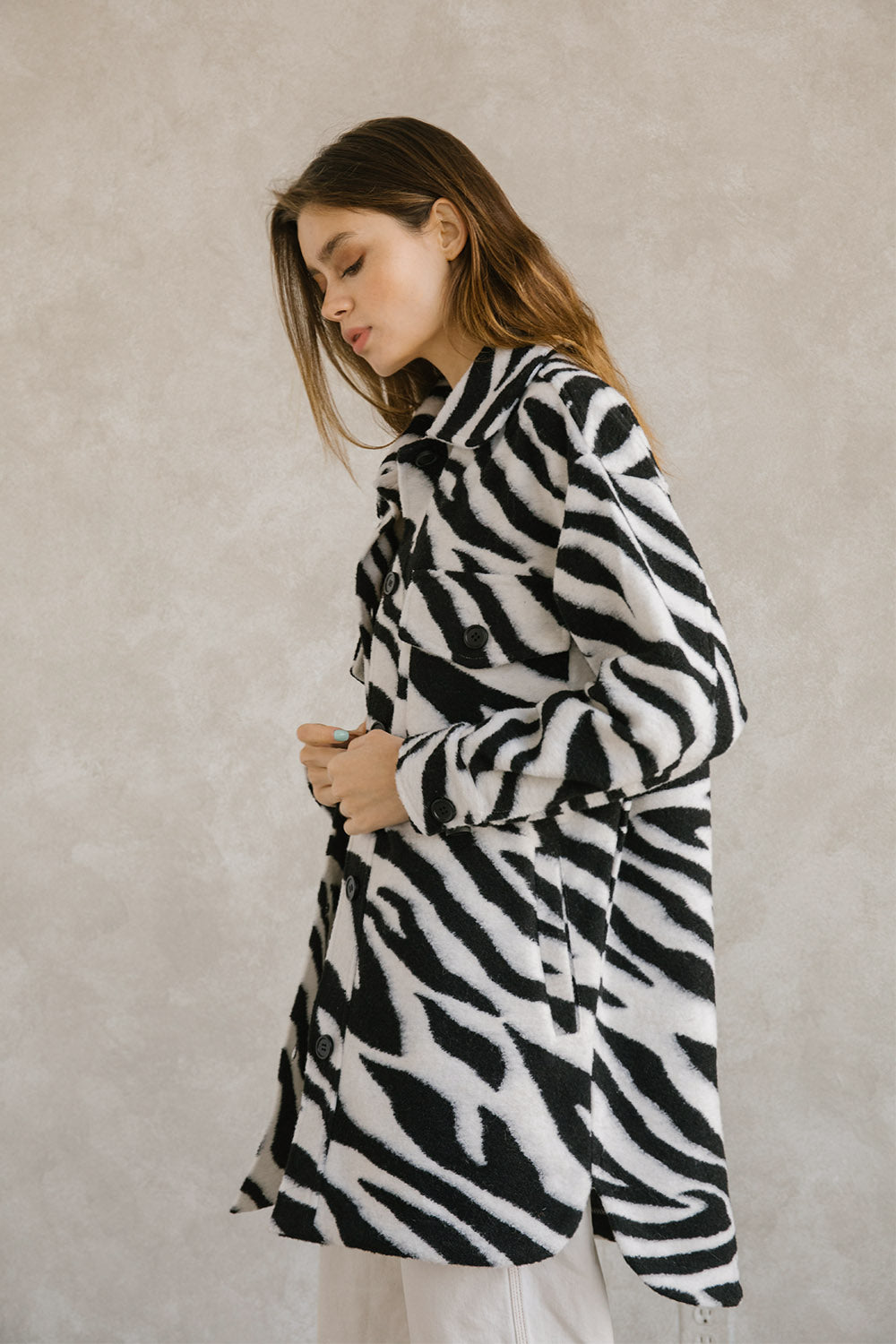 Side view of a woman wearing a zebra-patterned coat against a plain background